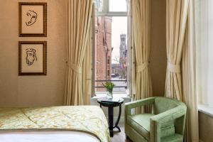 a bedroom with a bed and a chair and a window at Grand Hotel Casselbergh in Bruges