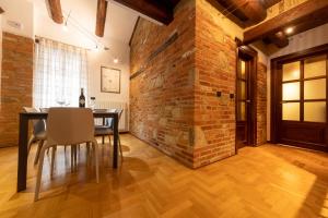 a dining room with a brick wall and a table and chairs at Peiragal in La Morra