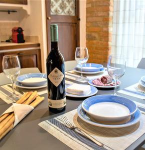 eine Flasche Wein auf einem Tisch mit Tellern und Gläsern in der Unterkunft Peiragal in La Morra