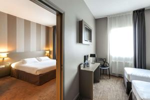 ビニックにあるBrit Hotel Le Galion & Spaのベッドと鏡が備わるホテルルーム