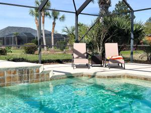 two chairs sitting next to a swimming pool at FairHaven Beach Retreat in Navarre