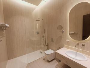 uma casa de banho com um WC, um lavatório e um espelho. em فندق ركايا للشقق الفندقية em Hail