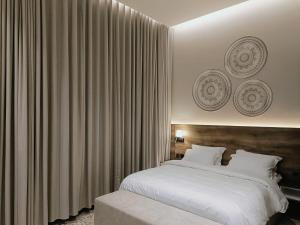 um quarto com uma grande cama branca e cortinas em فندق ركايا للشقق الفندقية em Hail
