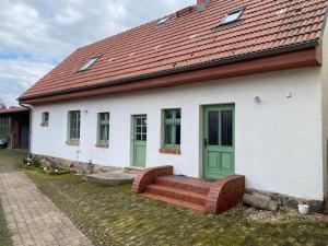 een wit huis met groene deuren en een bank bij Eisern Home 1 in Mittenwalde