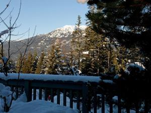 einen schneebedeckten Berg in der Ferne mit einem Zaun in der Unterkunft Mountain Modern Ski-in Walkout Condo with Private Hot Tub in Whistler