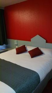 a bedroom with a large bed with a red wall at Brit Hotel Sarreguemines in Sarreguemines