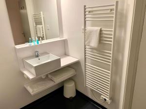 a white bathroom with a sink and a mirror at Brit Hotel Bordeaux Arena in Latresne