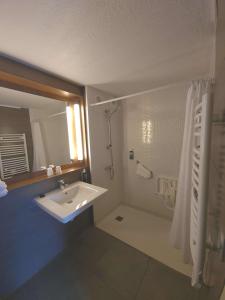 uma casa de banho branca com um lavatório e um chuveiro em Brit Hotel Confort Nancy Lunéville em Lunéville