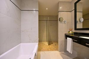 a bathroom with a tub and a shower and a sink at Grand Hotel Casselbergh in Bruges