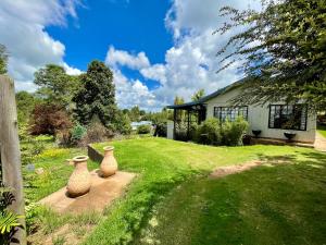 two vases sitting in the grass next to a house at The Hedge at Dullstroom Cottage in Dullstroom