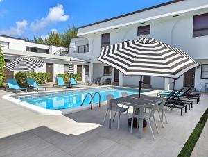 um pátio com uma mesa e guarda-sol ao lado de uma piscina em Pier Walk on Deerfield Beach Island em Deerfield Beach