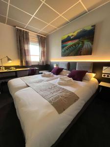 ヴズールにあるBRIT HOTEL LE VESOULの絵画が飾られたベッドルームの大きな白いベッド