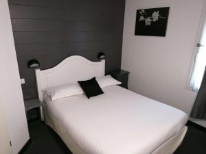 a bedroom with a white bed with a black pillow at Brit Hotel Essentiel Albi Parc des Expos in Le Sequestre
