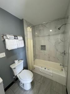 a bathroom with a toilet and a shower and a tub at Rodeway Inn Moosic - Scranton in Moosic