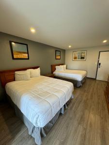 una camera d'albergo con due letti con lenzuola bianche di Rodeway Inn Moosic - Scranton a Moosic