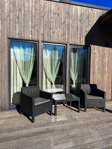 a patio with two chairs and a table and two windows at Silazari Klapkalnciems in Klapkalnciems