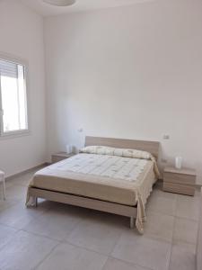 een witte slaapkamer met een bed en een raam bij VILLA BIANCA Porto Cesareo in Porto Cesareo