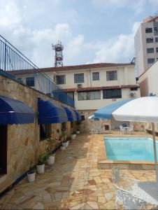 un hôtel avec une piscine et des parasols bleus dans l'établissement Suíte Hotel São José, à Caxambu