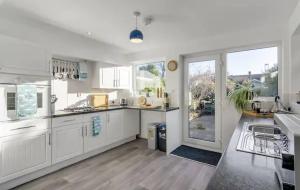 a kitchen with white cabinets and a large window at Turnstones - Seaside Home - Free Street Parking in Sheringham