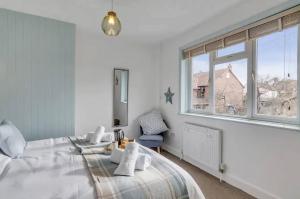 a white bedroom with a large bed and a window at Turnstone Retreat - Parking in Sheringham
