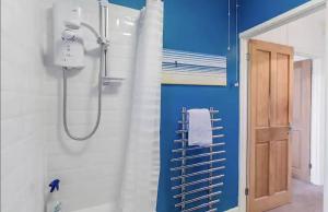 a shower in a bathroom with a blue wall at Cosy and Fresh Seaside Home - Parking in Sheringham +12 photos