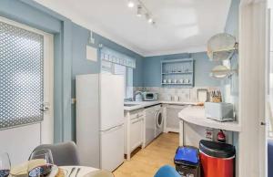 a kitchen with blue walls and a white refrigerator at Turnstone Retreat - Parking in Sheringham