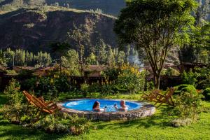 dos personas sentadas en una piscina en un jardín en Lamay Lodge, en Cusco