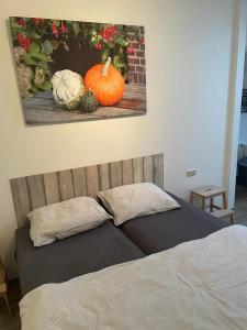 a bed with pumpkins and a picture on the wall at Appartement Pieterom in Sleen