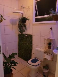 a bathroom with a toilet and a window and plants at Casa com piscina aconchegante in Ribeirão Preto