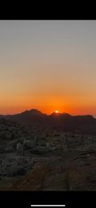 a view of a city with the sunset in the background at Over Mountains Hotel in Wadi Musa