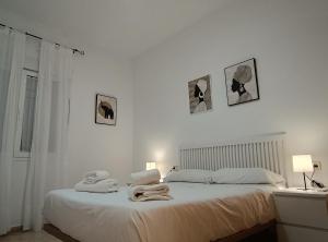 une chambre blanche avec un lit avec des serviettes dessus dans l'établissement SunShine Fernando Colon, à Cordoue