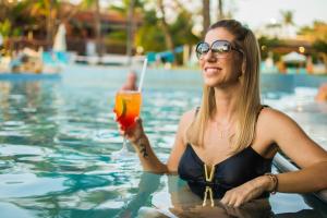 a woman holding a drink in a swimming pool at Blue Tree Thermas de Lins Resort in Lins