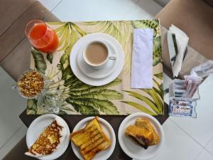 a table with plates of food and a cup of coffee at Temporada In Natal - Pousada in Natal