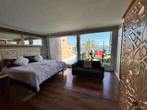 una camera da letto con un letto e una sedia e una grande finestra di Pacificsunset Reñaca a Viña del Mar