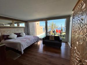 a bedroom with a bed and a chair and a large window at Pacificsunset Reñaca in Viña del Mar