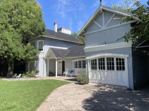 une grande maison blanche avec un garage blanc dans l'établissement Casa Leloir, à Villa Leloir