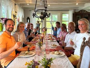 een groep mensen die rond een tafel met wijnglazen zitten bij Villa Solvorn in Solvorn