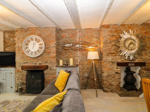 a living room with a couch and a clock on a brick wall at Pebble Bay in Brixham