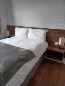 een slaapkamer met een groot bed met witte lakens en kussens bij The Watling Inn in Nuneaton
