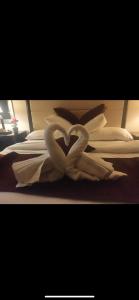 two white swans forming a heart on a bed at Over Mountains Hotel in Wadi Musa
