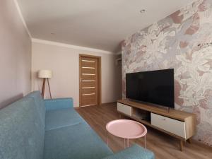 a living room with a blue couch and a tv at Apartament Parkowe Love in Chorzów