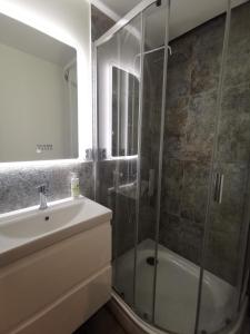 a bathroom with a glass shower and a sink at Apartament Parkowe Love in Chorzów