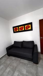 un sofá negro en una habitación con dos fotos en la pared en Apartamentos Mamma Mia, en Córdoba