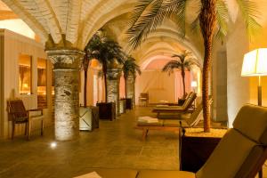 a lobby with palm trees in a building at Grand Hotel Casselbergh in Bruges
