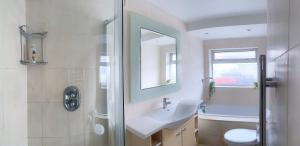 y baño con lavabo, aseo y ducha. en Modern four bedroom semi-detached house with off street parking 8 min drive to Wembley stadium, 5 miles to Central London, en Londres