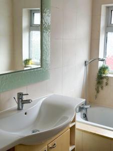 a bathroom with a sink and a bath tub at Modern four bedroom semi-detached house with off street parking 8 min drive to Wembley stadium, 5 miles to Central London in London