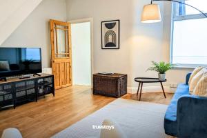 uma sala de estar com um sofá azul e uma televisão em Crawford House - Stunning 2 Bedroom House in Manchester em Manchester