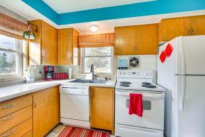 a kitchen with white appliances and wooden cabinets at Birchwood Cottage with Red Cedar Lake Access! in Birchwood