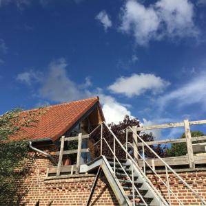 een stenen huis met een ladder aan de zijkant bij Gîte la Luchette - petit village médiéval de la Somme in Lucheux