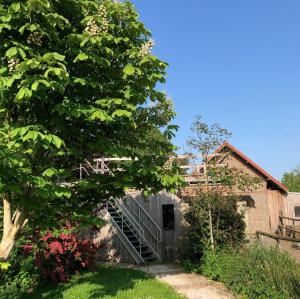 een huis met een trap naast een boom bij Gîte la Luchette - petit village médiéval de la Somme in Lucheux